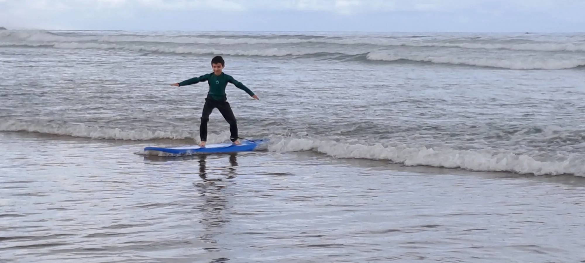 Simo coaching a circle of surf-week guests in the sand, explaining tide and lineup positioning